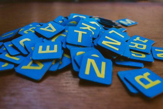 A collection of colorful blue letter tiles randomly stacked on a wooden surface.