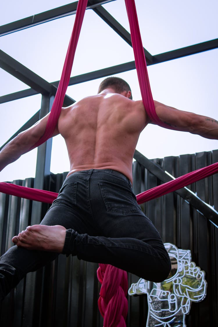 A Shirtless Man Doing Aerial Fabric Workouts