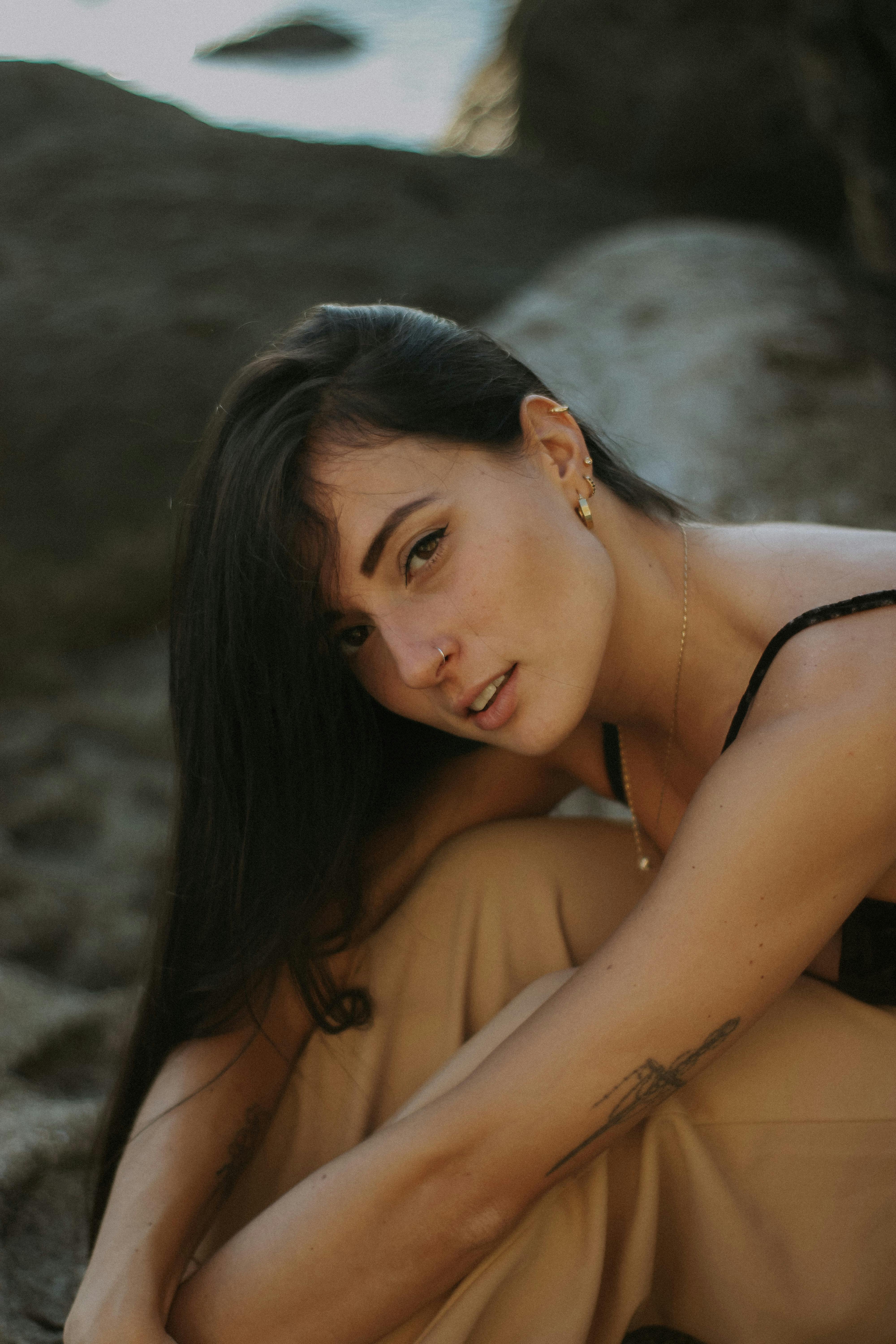 Beautiful outdoor portrait of a young woman with long hair, tattoos, and an engaging gaze.