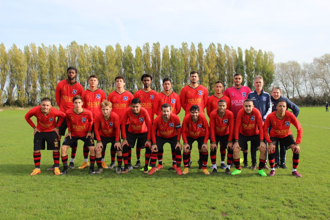 a local soccer team posing on a sunny day on the field