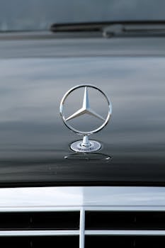 Detailed view of a Mercedes-Benz emblem on a car hood with sleek design.