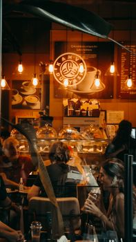 Warmly lit urban cafe with people enjoying their visit, showcasing the lively ambiance of social dining.