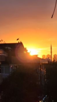Dramatic sunset over city skyline with silhouetted buildings and vibrant sky.
