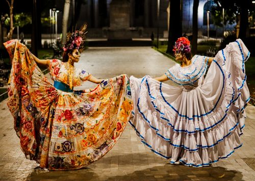 Free Two women in traditional dresses celebrate Day of the Dead with colorful costumes in a lively street scene. Stock Photo