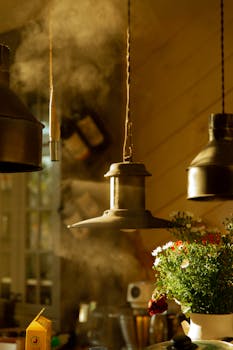 Warm kitchen scene showing metal lights, plants, and steam rising, evoking rustic charm.