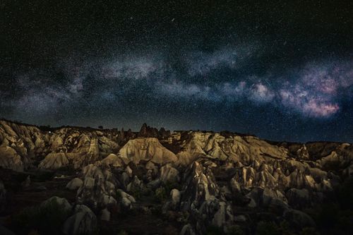 Free A breathtaking view of the Milky Way over dramatic rock formations under a starry night sky. Stock Photo