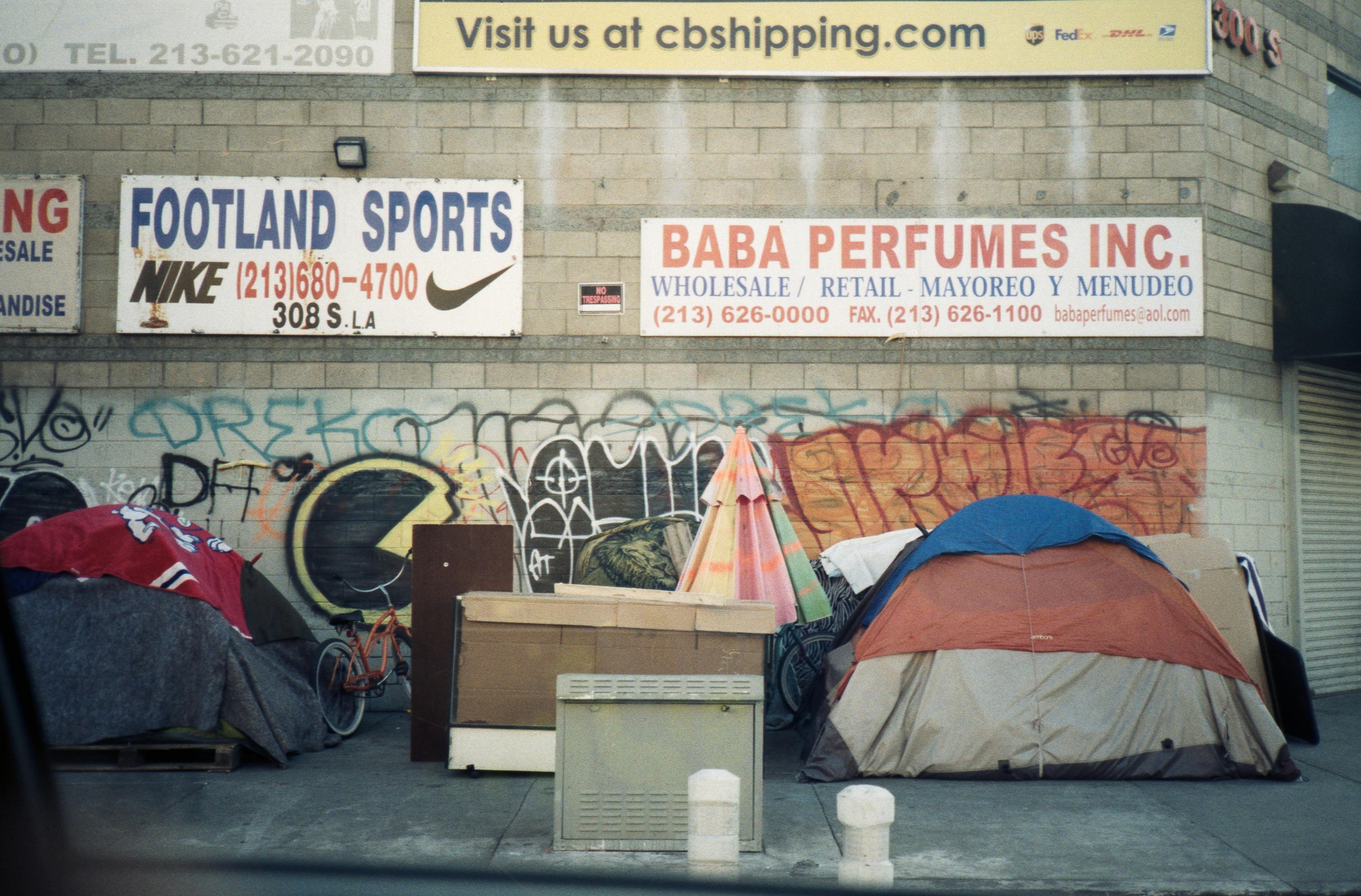 Street view showcasing tents and graffiti in an urban setting with visible signages.