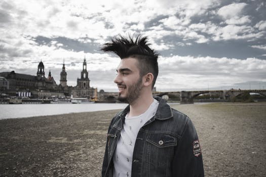 一位发型独特的年轻人，在德累斯顿天际线的背景下，于河边微笑