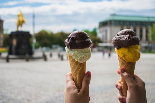 Photography of Person Holding Two Ice Cream