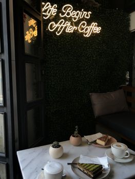 A cozy café in Istanbul with a neon 'Life Begins After Coffee' sign and coffee served on a table.