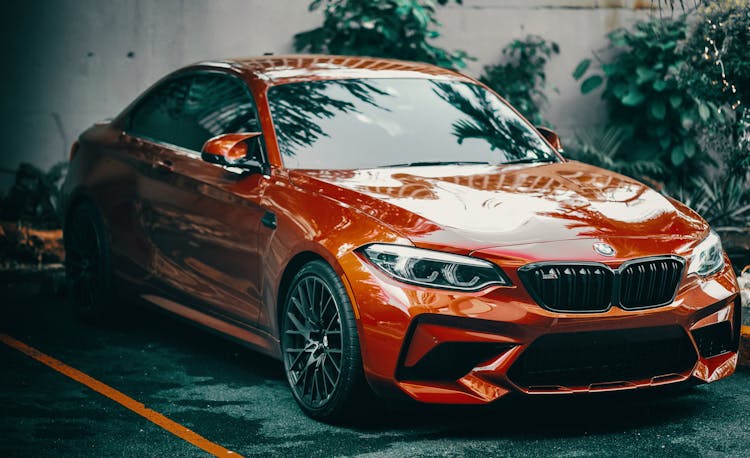 Red Bmw Car Parked On The Asphalt Pavement