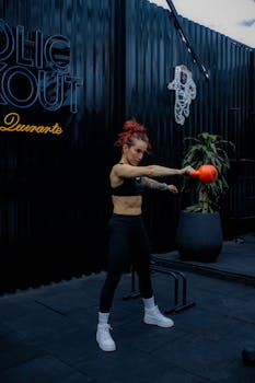 Athletic woman working out with a kettlebell in an outdoor gym, wearing sportswear.