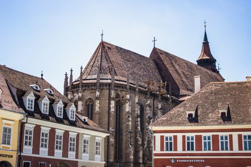 Free View of the Black Church in Brașov with distinct medieval architecture against a clear blue sky. Stock Photo