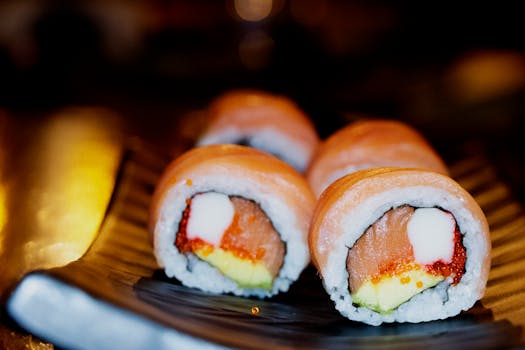 Close-up view of delicious salmon sushi rolls with creamy filling and avocado on a decorative plate.