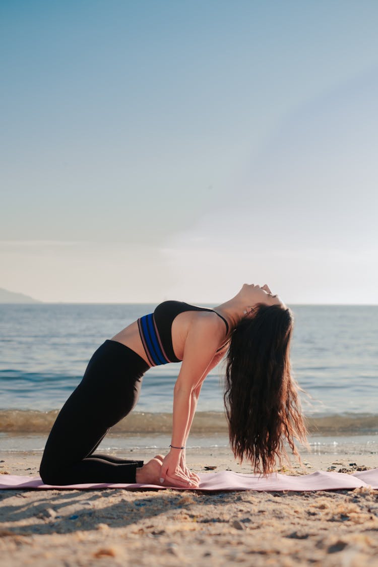 A Woman In Black Leggings Doing Yoga On The Beach