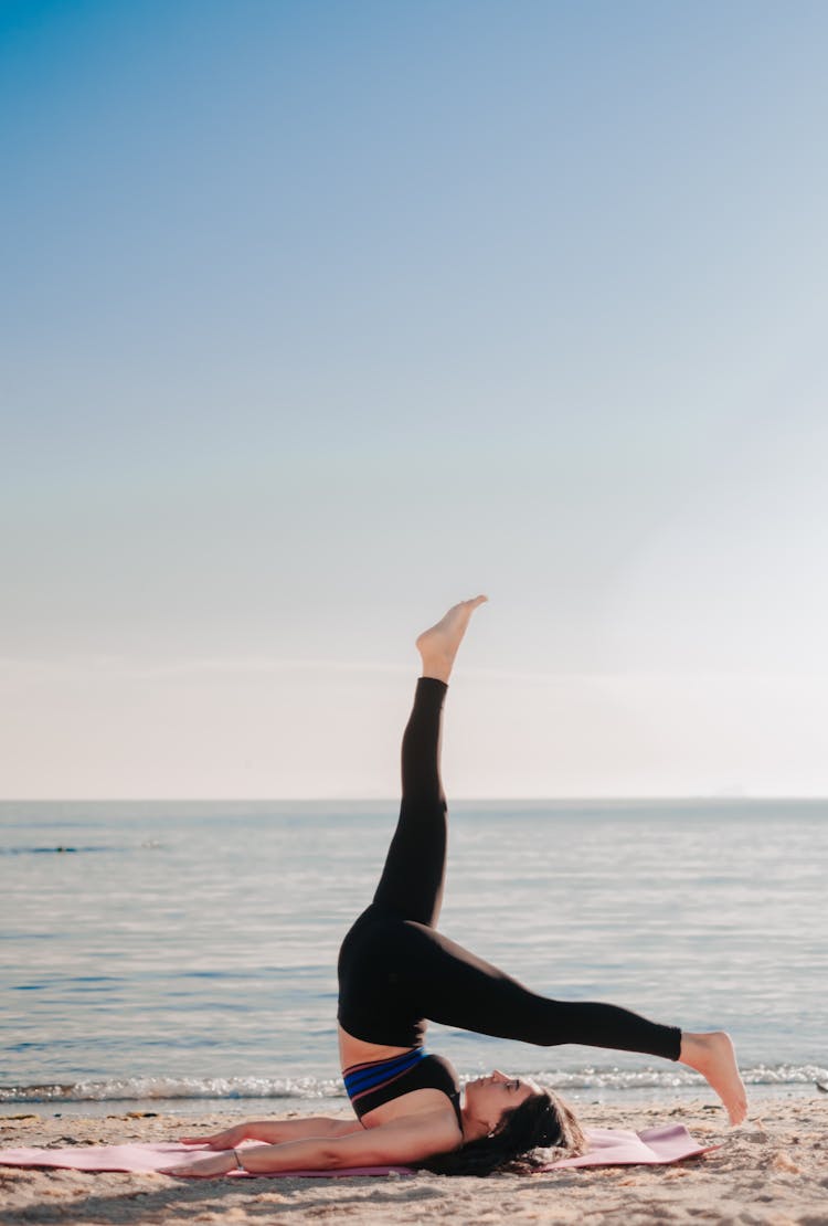 Woman Practicing Yoga On Beach