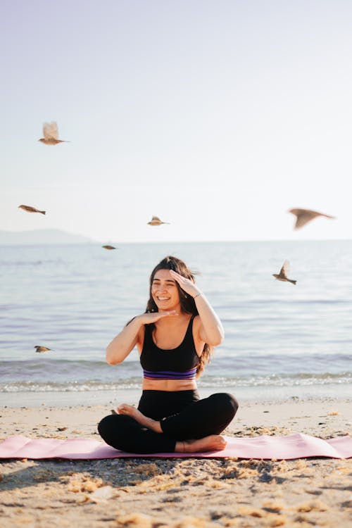 Woman Sitting on Mat on Beach