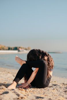 A woman practicing yoga on a sunny beach, embodying a peaceful and healthy lifestyle.