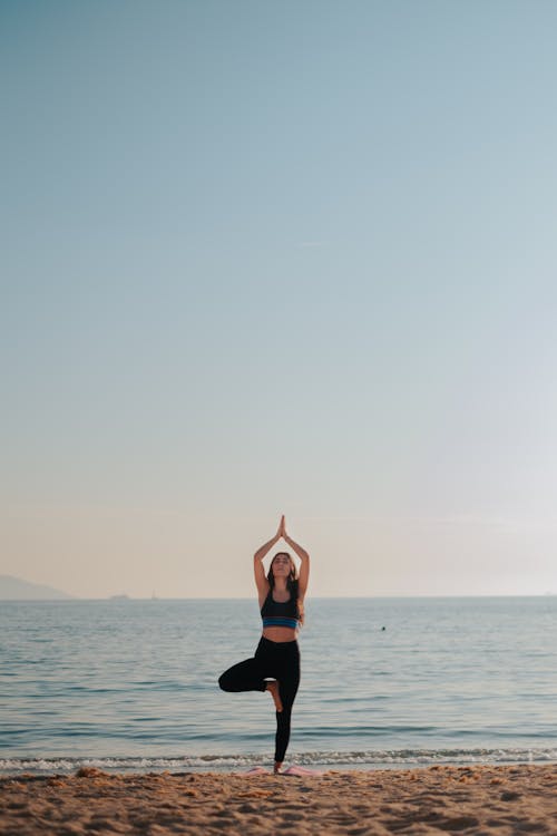 Free Woman Practicing Yoga on Beach Stock Photo