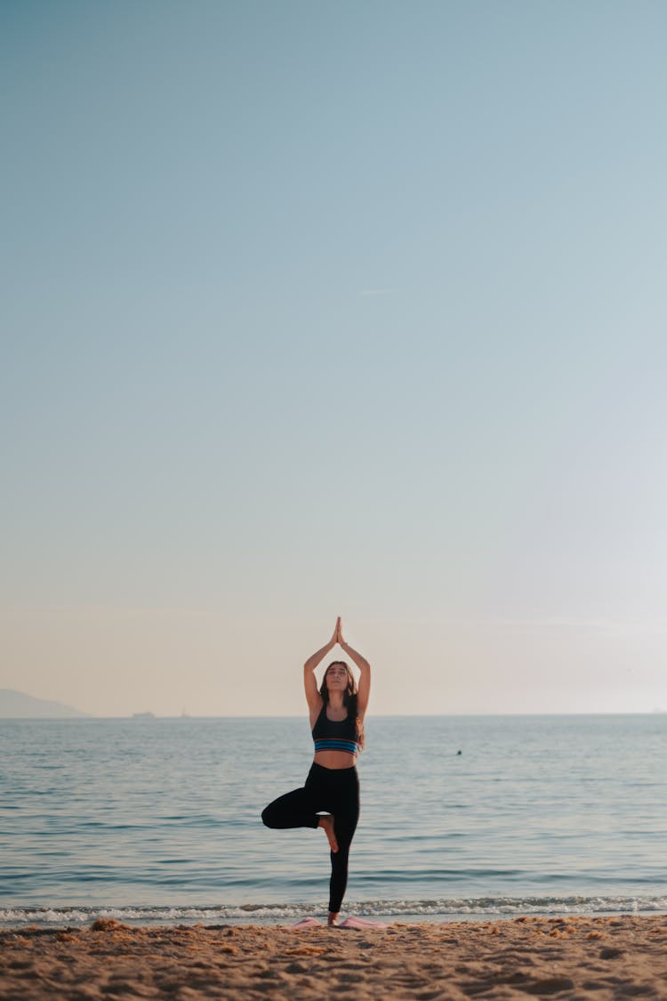 Woman Practicing Yoga On Beach