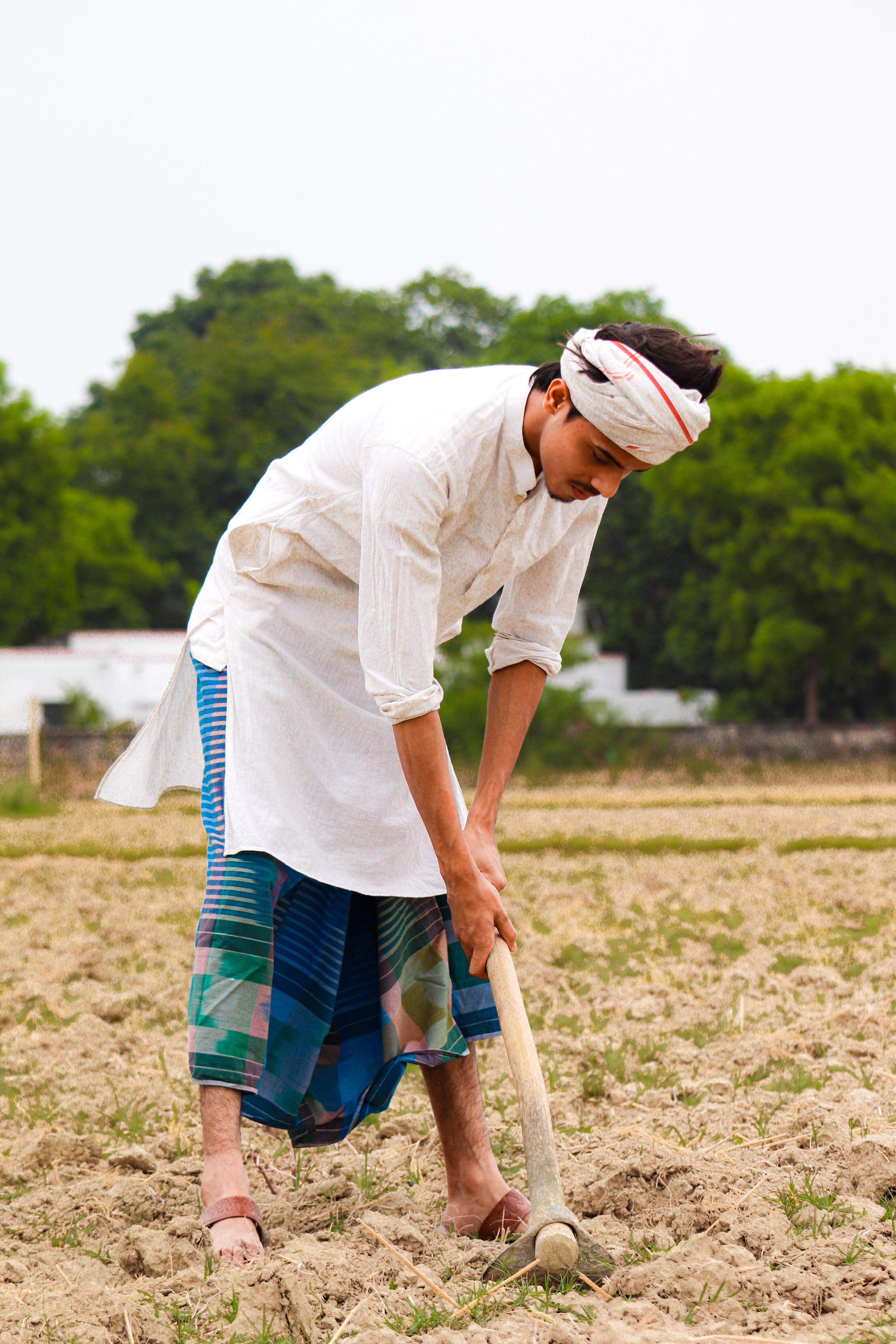 Asian man in traditional clothing farming in a rural field.