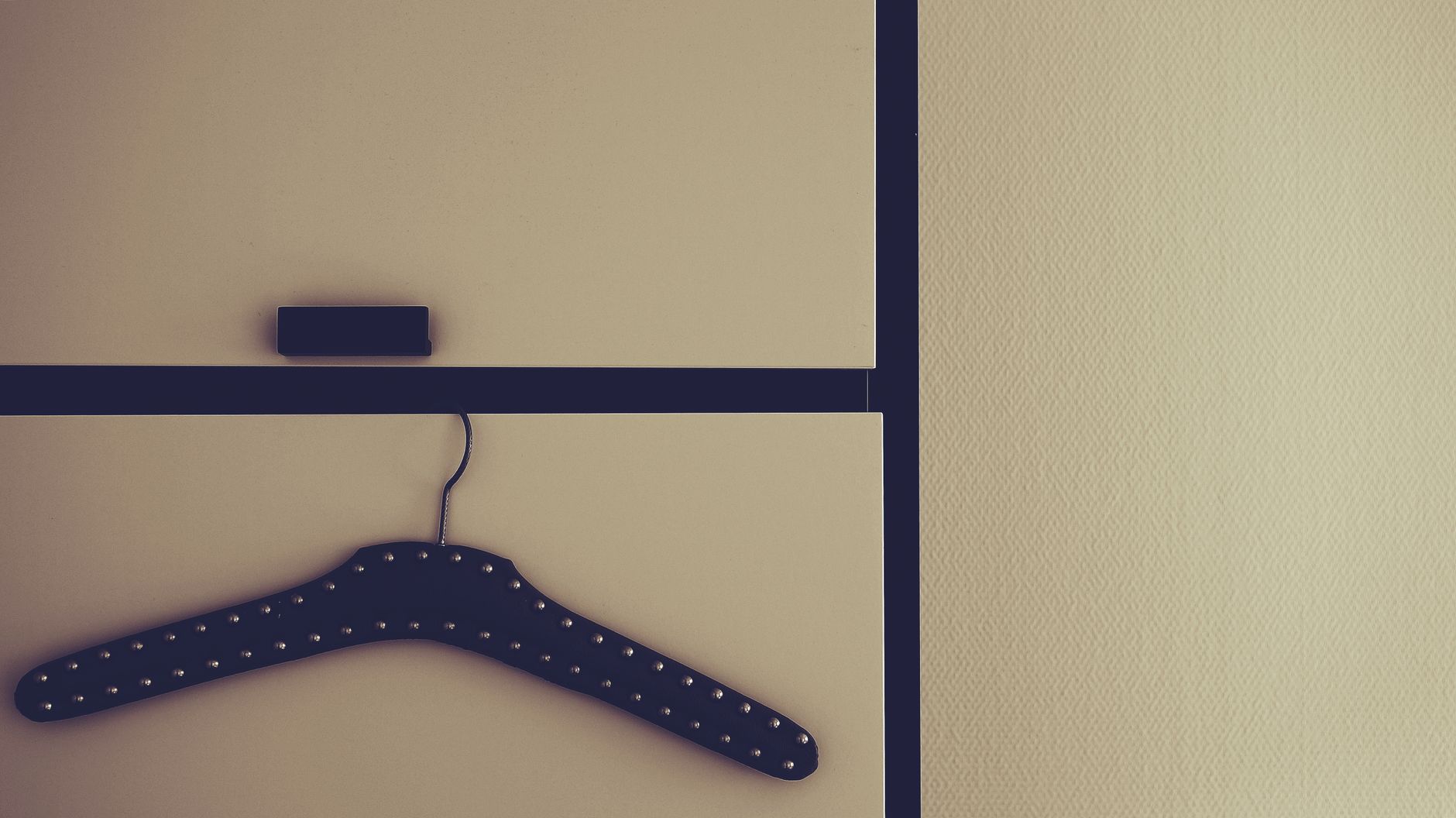 A minimalist wardrobe with a studded hanger and cabinet door, perfect for home decor themes.
