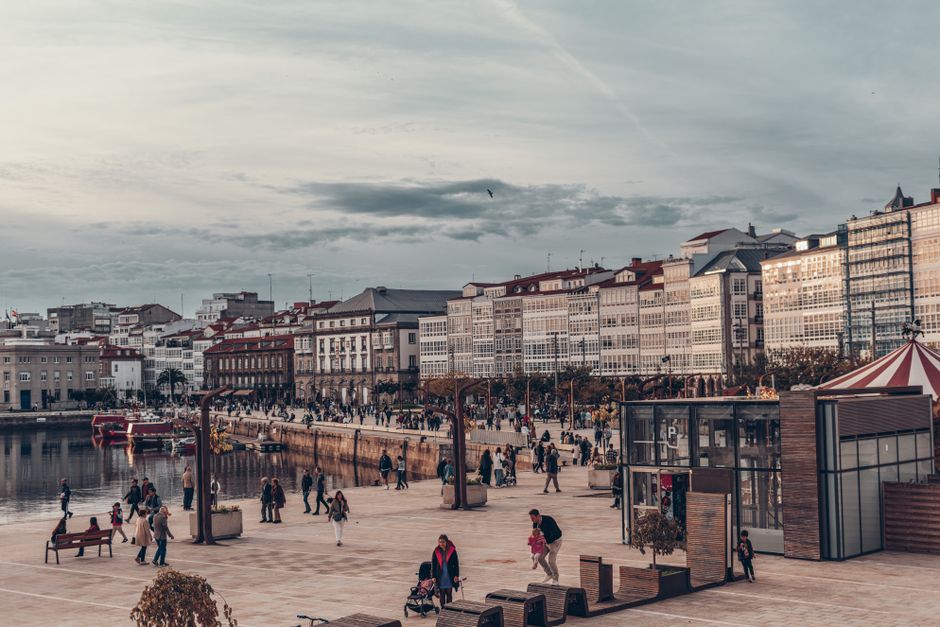 Un bullicioso paseo europeo con edificios de estilo colonial y personas disfrutando de un puerto escénico.