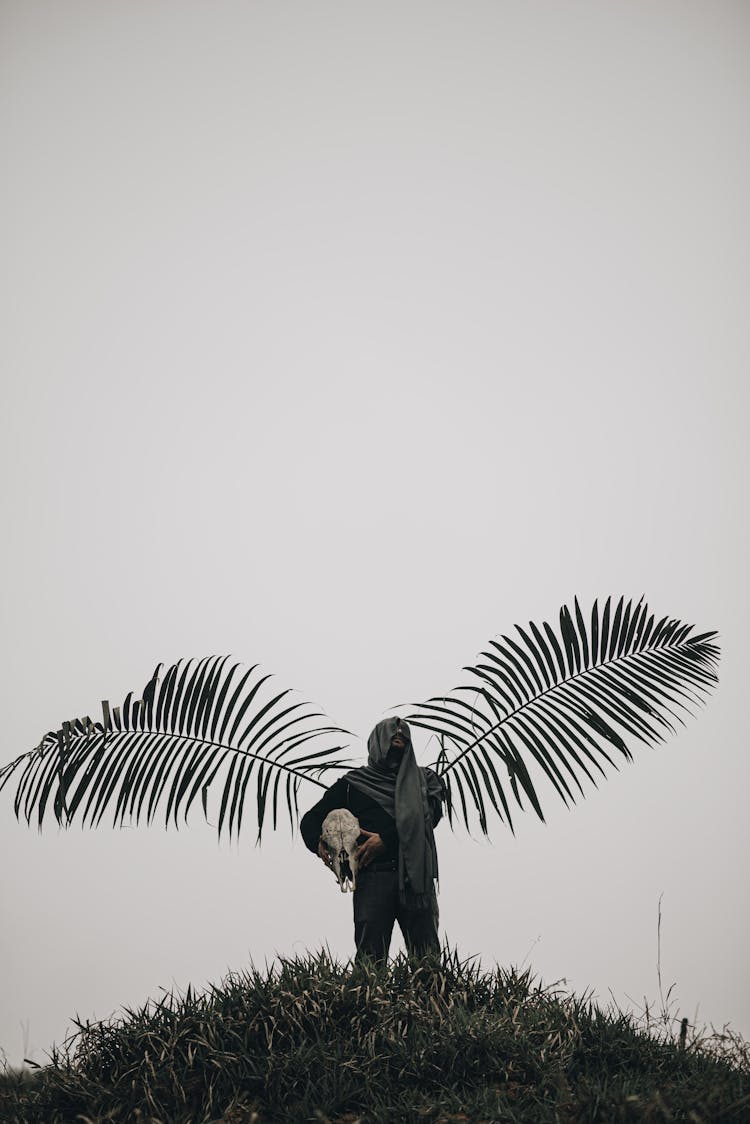 Man With Palm Tree Leaves Standing On Hill