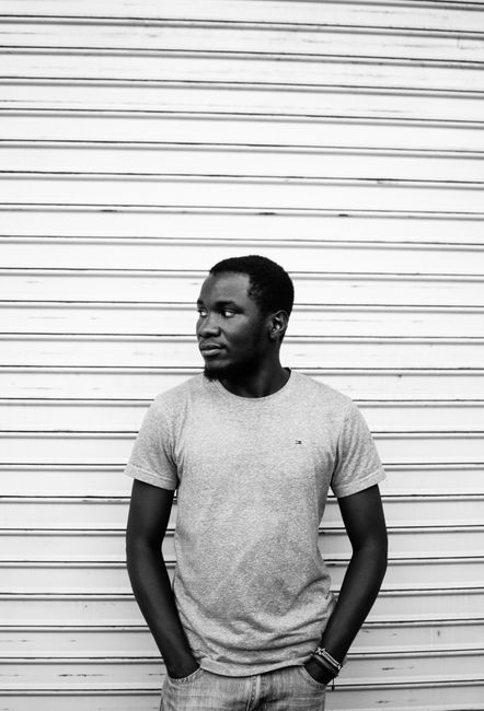 Black and white portrait of a thoughtful man standing in casual attire against a corrugated shutter. Urban style.