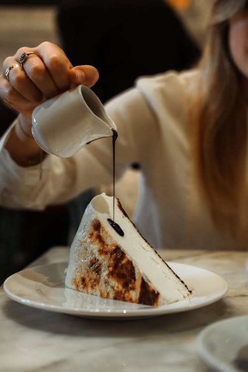 Free A Person Pouring a Chocolate Syrup on a Sliced Cake Stock Photo