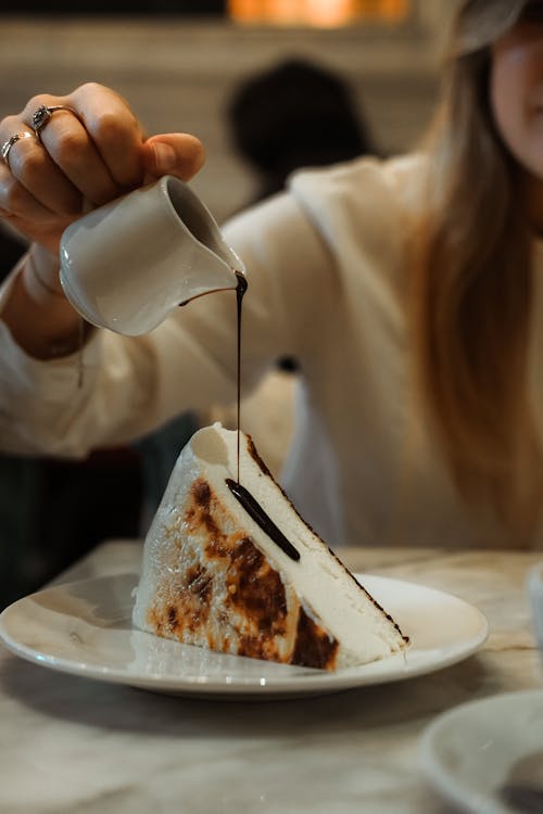 Free A Person Pouring a Chocolate Syrup on a Sliced Cake Stock Photo