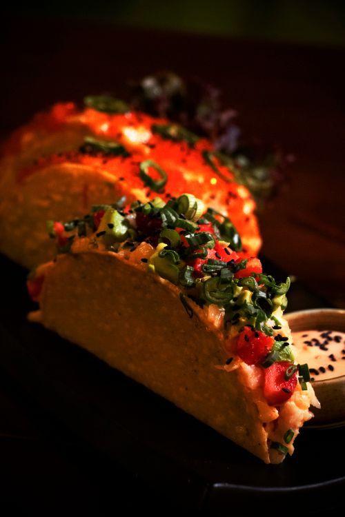 Free Savor the vibrant flavors of gourmet tacos topped with fresh ingredients and served with dipping sauce. Stock Photo