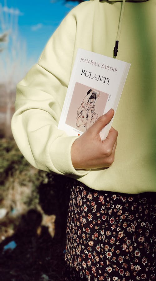 A Woman in Yellow Sweater Holding White Book