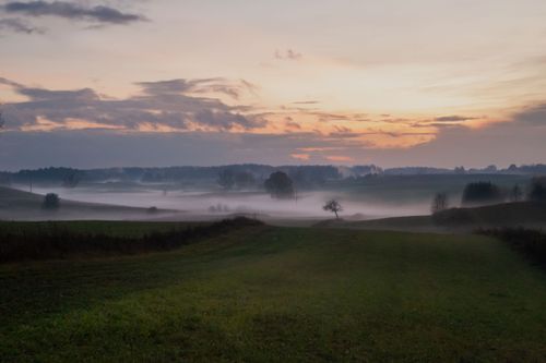 Free A picturesque sunrise over a foggy landscape, capturing the serene beauty of nature. Stock Photo