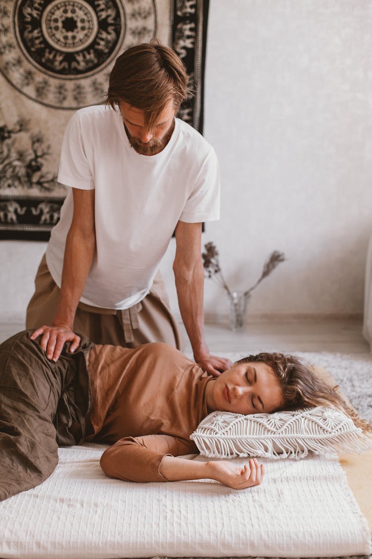 Man Massaging Woman Lying On Pillow