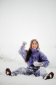 A cheerful woman in a blue jacket having fun in the snow during winter.