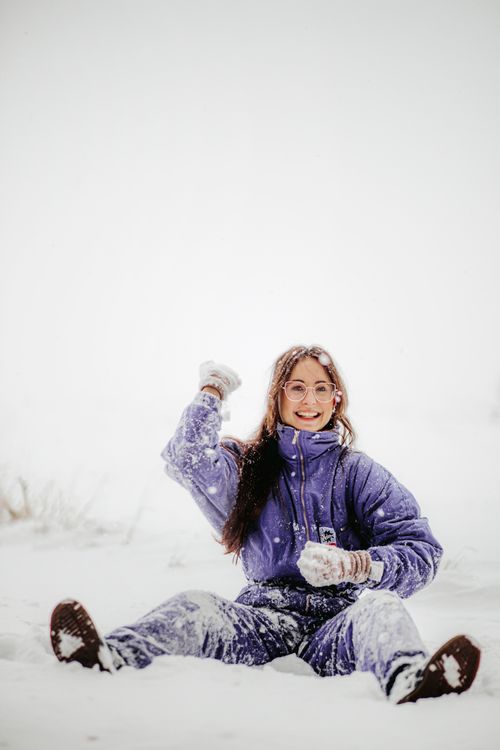Free A cheerful woman in a blue jacket having fun in the snow during winter. Stock Photo