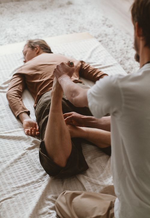 Free Therapist helps client stretch during a physiotherapy session indoors. Stock Photo