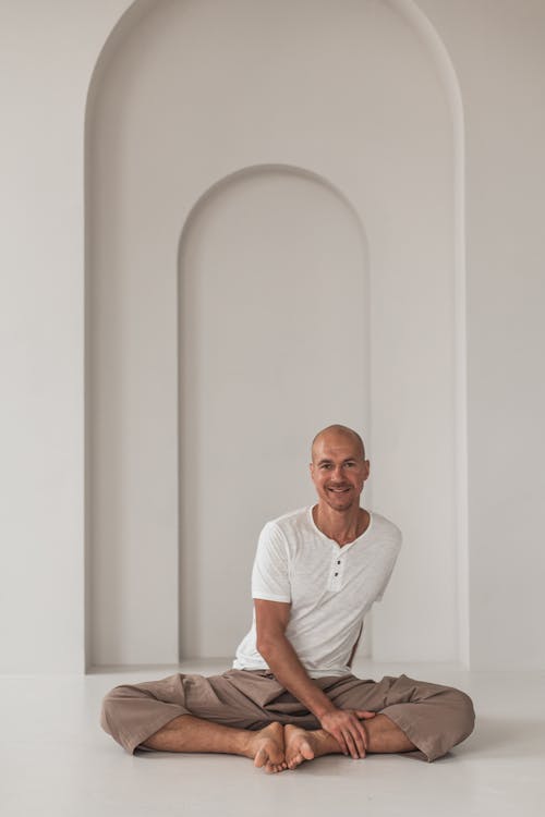 A Man in White Shirts and Brown Pants Sitting on the Concrete Floor