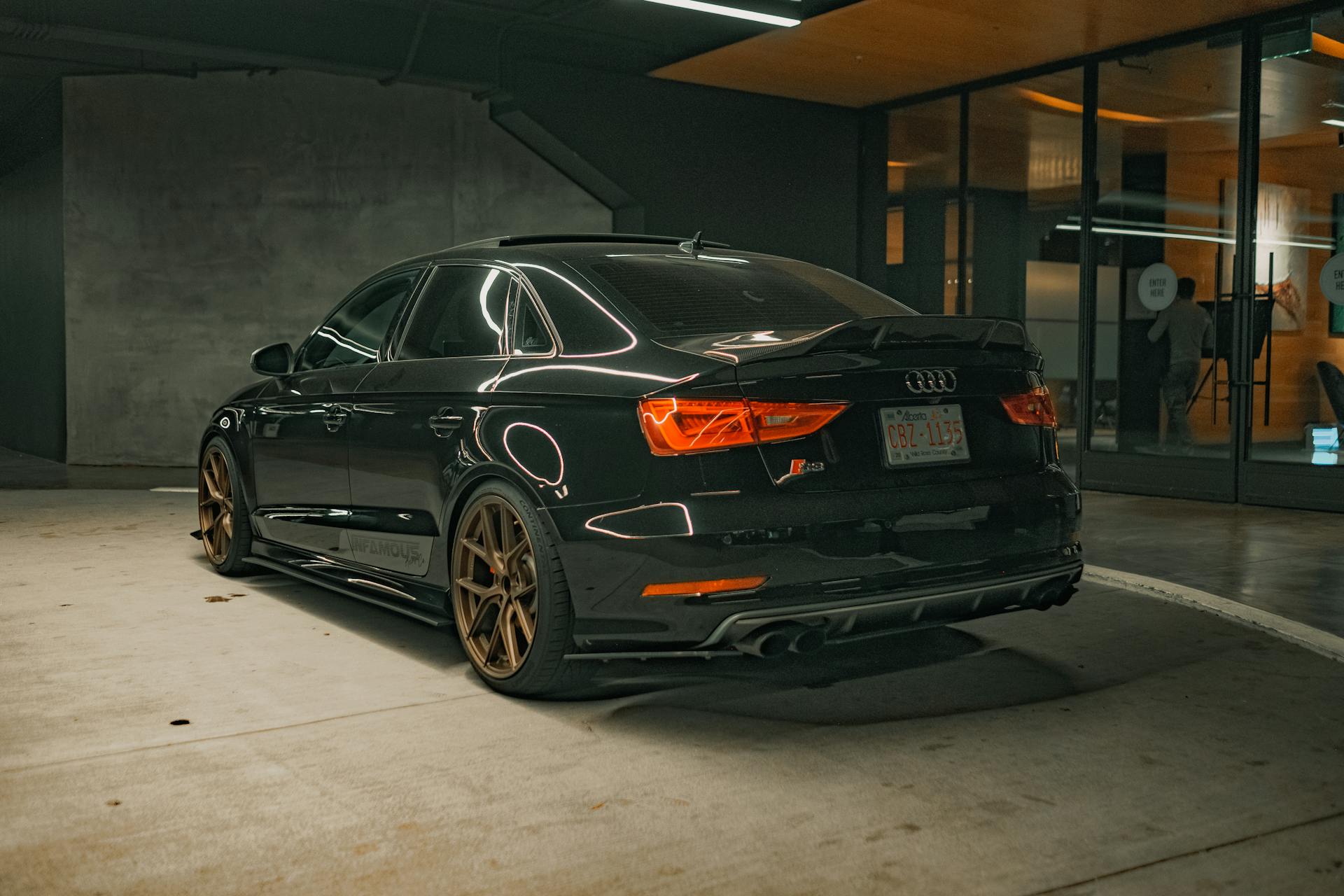 Black Audi sedan with shiny finish parked indoors at night. Stylish and modern car in an urban setting.