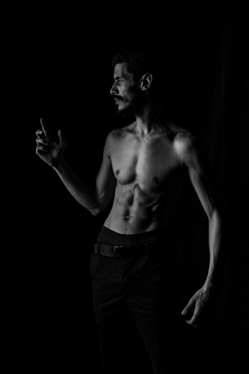 Grayscale Photo of a Topless Man on Black Background