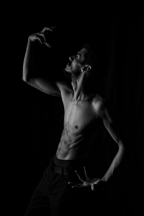 Free A striking black-and-white portrait of a shirtless man posing artistically against a dark background. Stock Photo