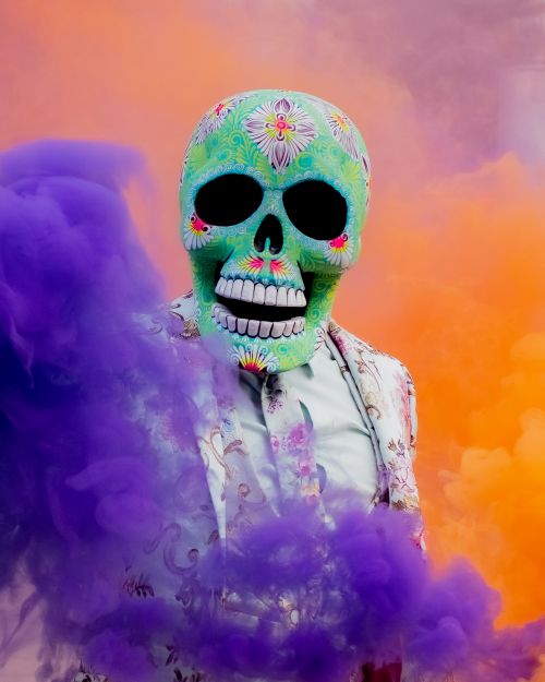 Free Colorful Dia de los Muertos skull mask with purple smoke for Halloween. Stock Photo