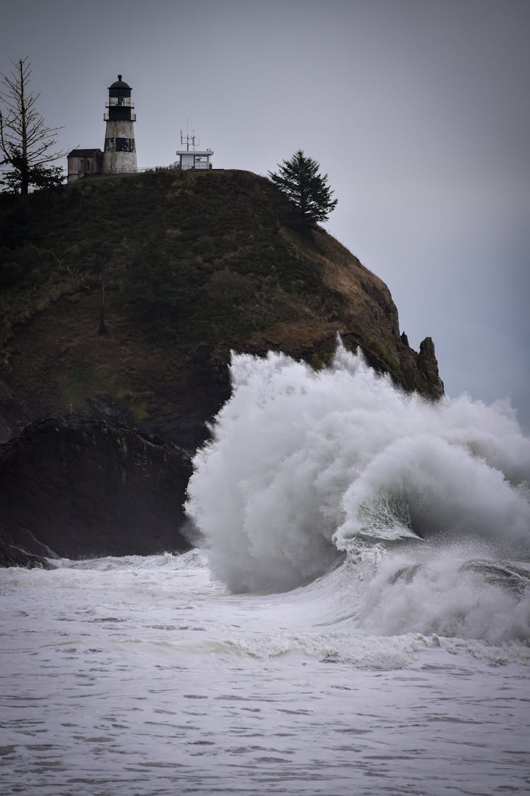 Waves Crashing Onto Cliff With Lighthouse