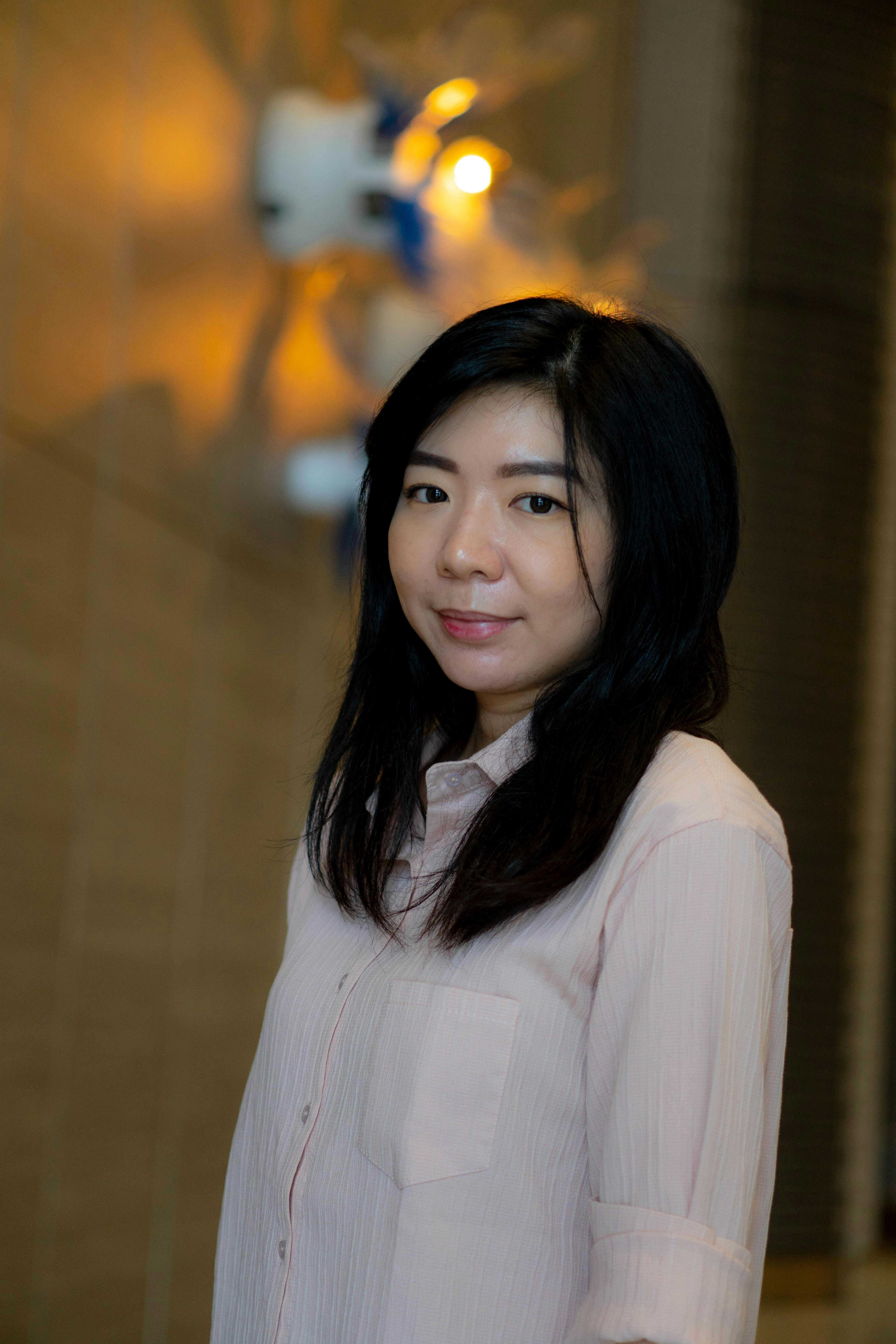 A smiling woman poses indoors with a soft glow, creating a warm and inviting atmosphere.
