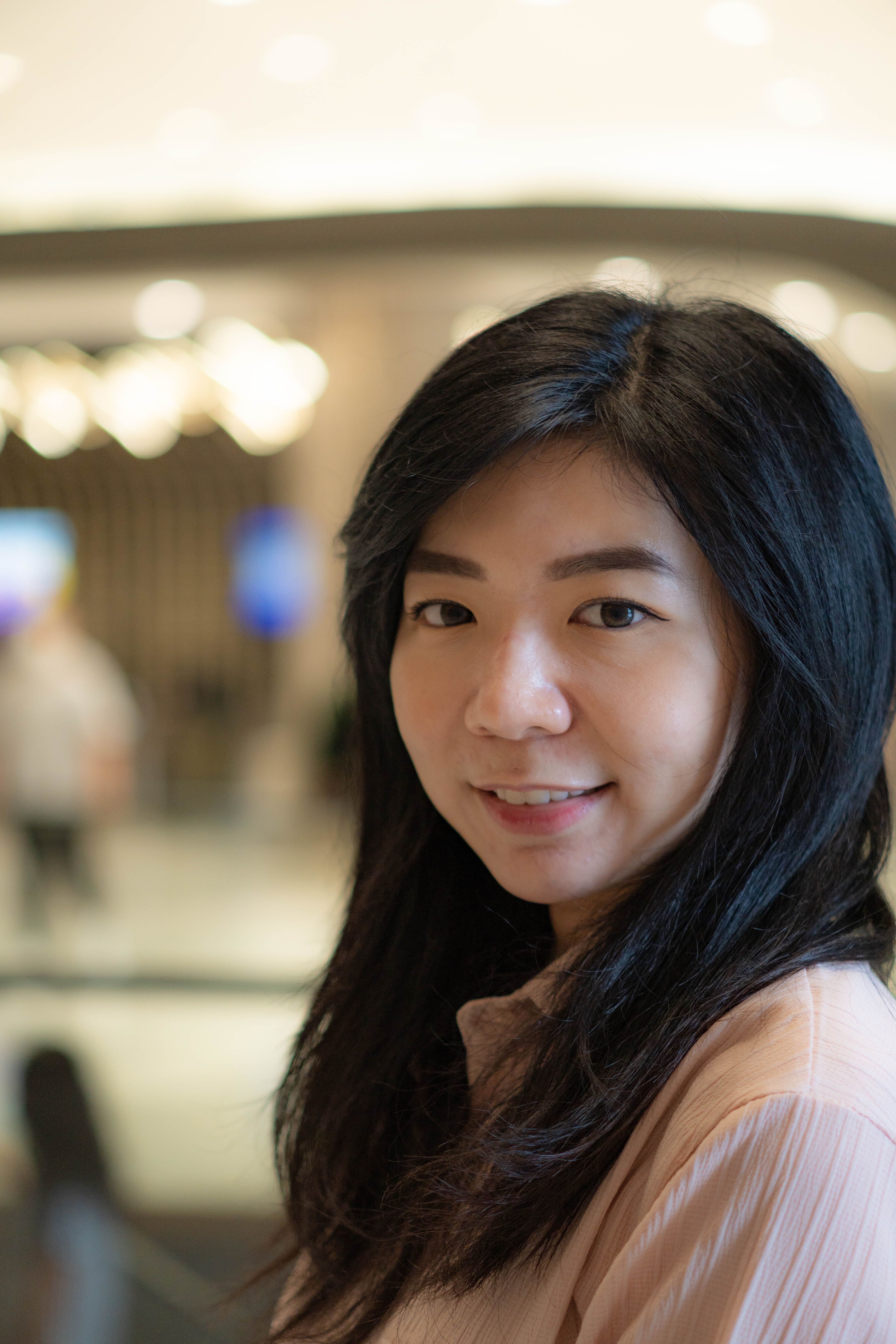 Bright portrait of a smiling young woman with long hair in an indoor setting.