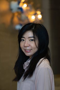 Portrait of a smiling woman with long hair indoors, warm lighting.