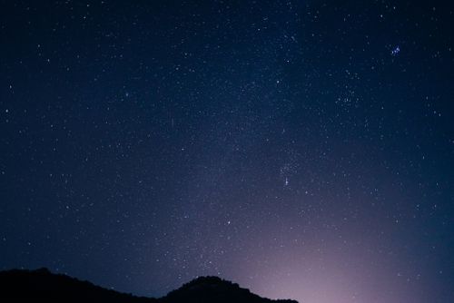 Free Serene starry night sky with a mountain silhouette, capturing the vast expanse of the universe. Stock Photo