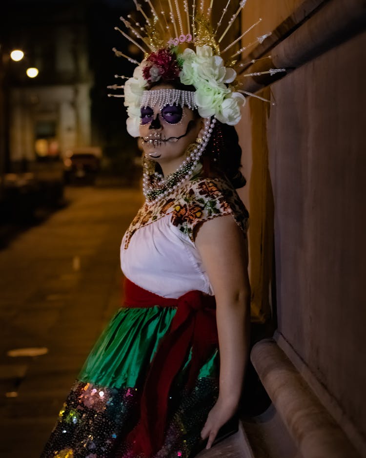 A Woman Standing On The Street At Night While Wearing Costume