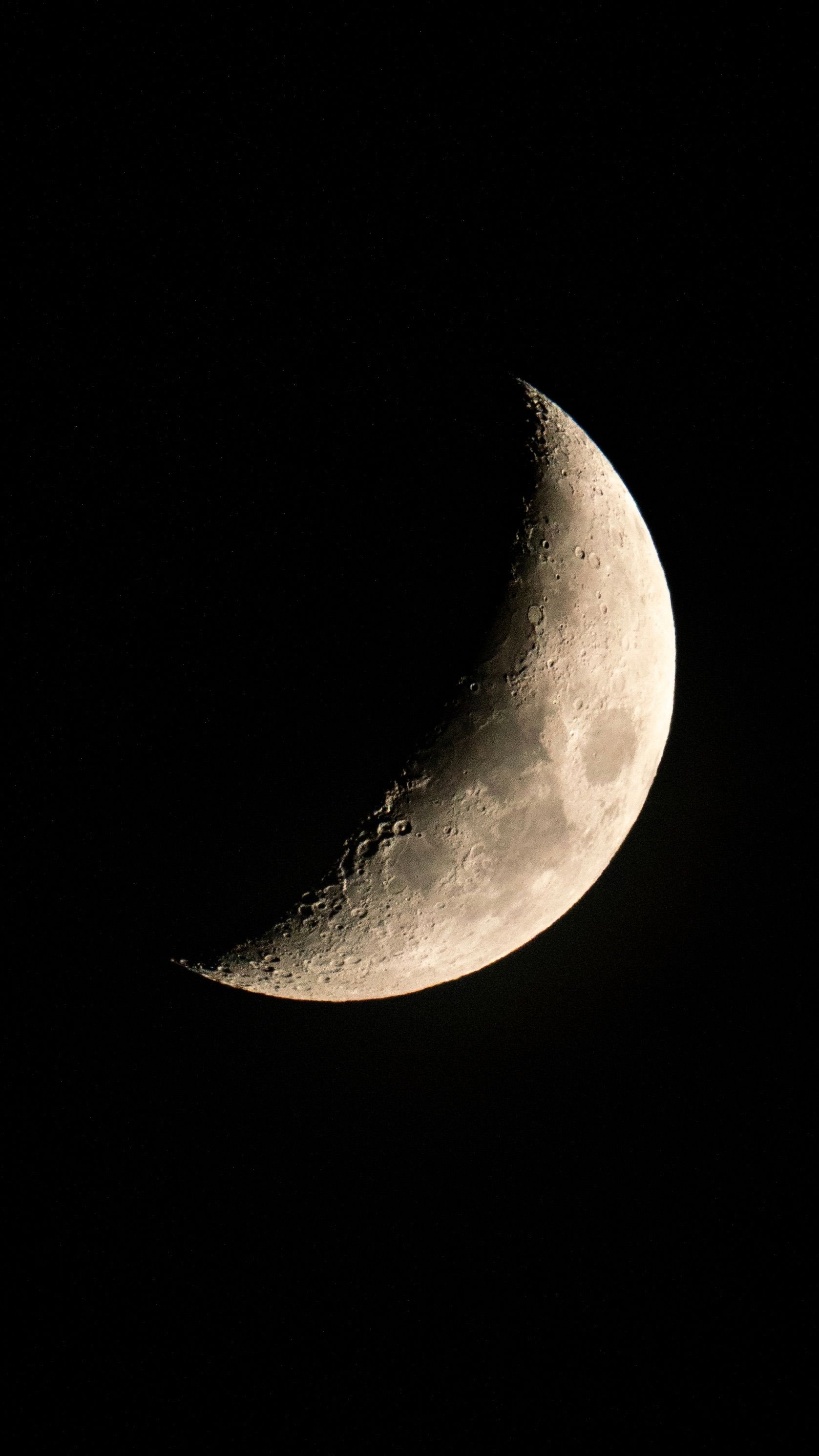 Close-up of a crescent moon against a dark night sky, showing detailed lunar surface.